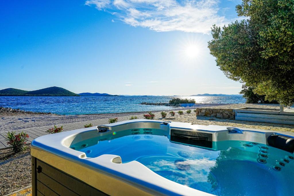 una vasca idromassaggio con vista sull'acqua di BUQEZ ECO RESORT - Beach Villa 28 - Directly by beach a Drage