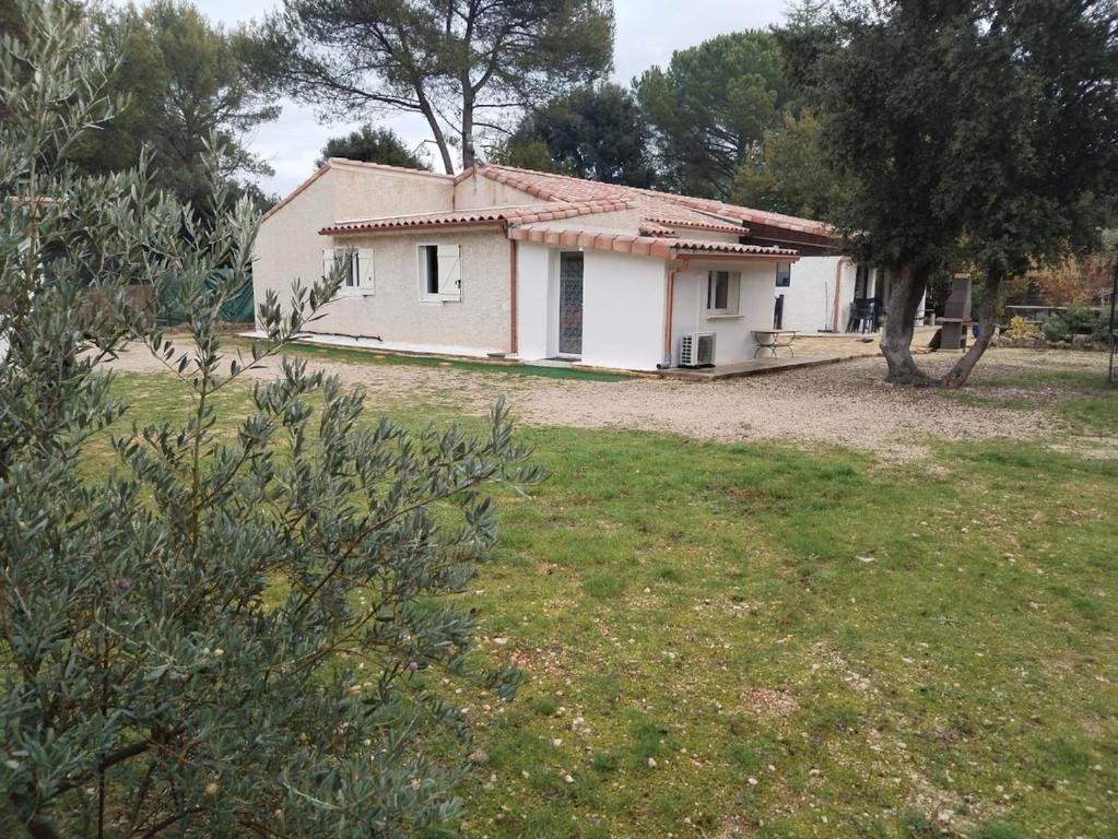une petite maison blanche avec une cour gazonnée dans l'établissement Studio garrigue saint didier, à Saint-Didier