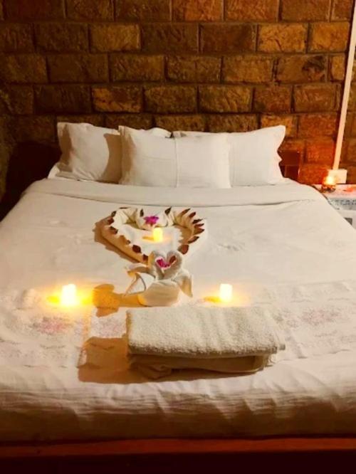 a bed with two candles and a cake on it at Smoky Falls Mae Fi Resort in Cherrapunji