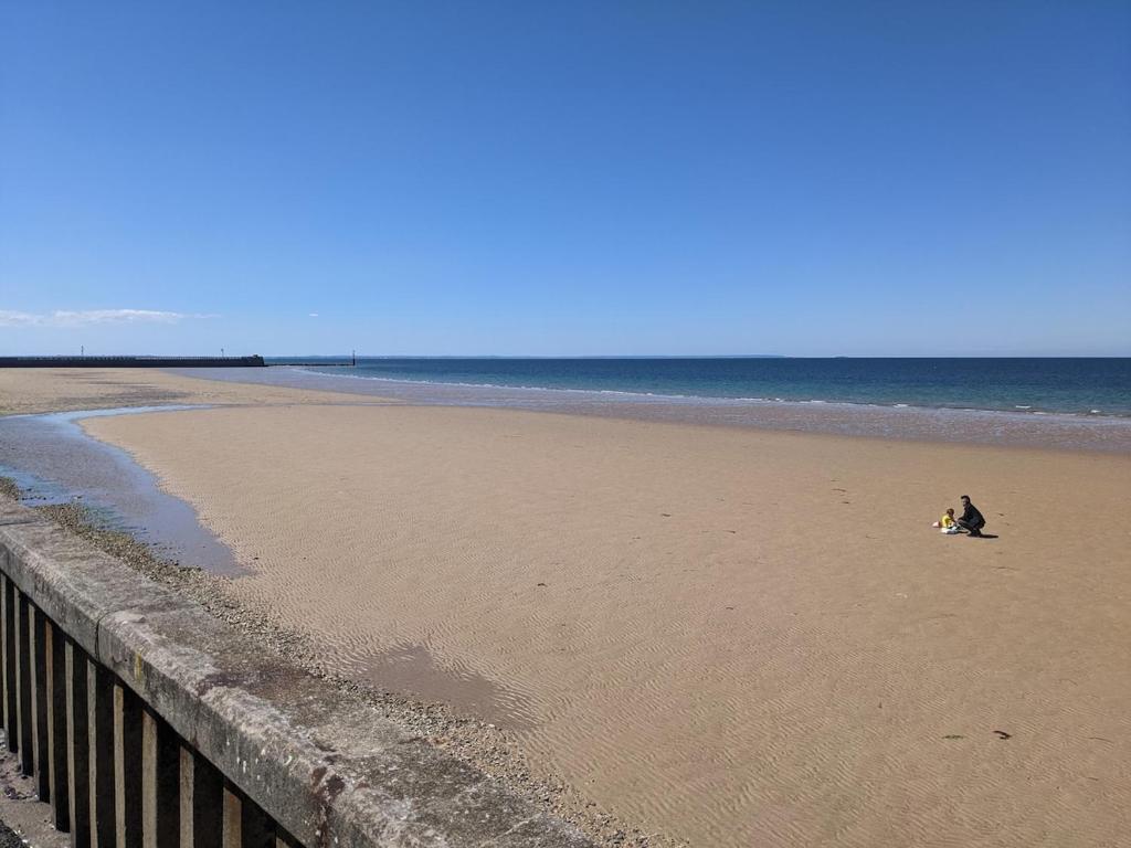 a person sitting on a beach next to the ocean at Studio à 50M de la mer avec SPA in Grandcamp-Maisy