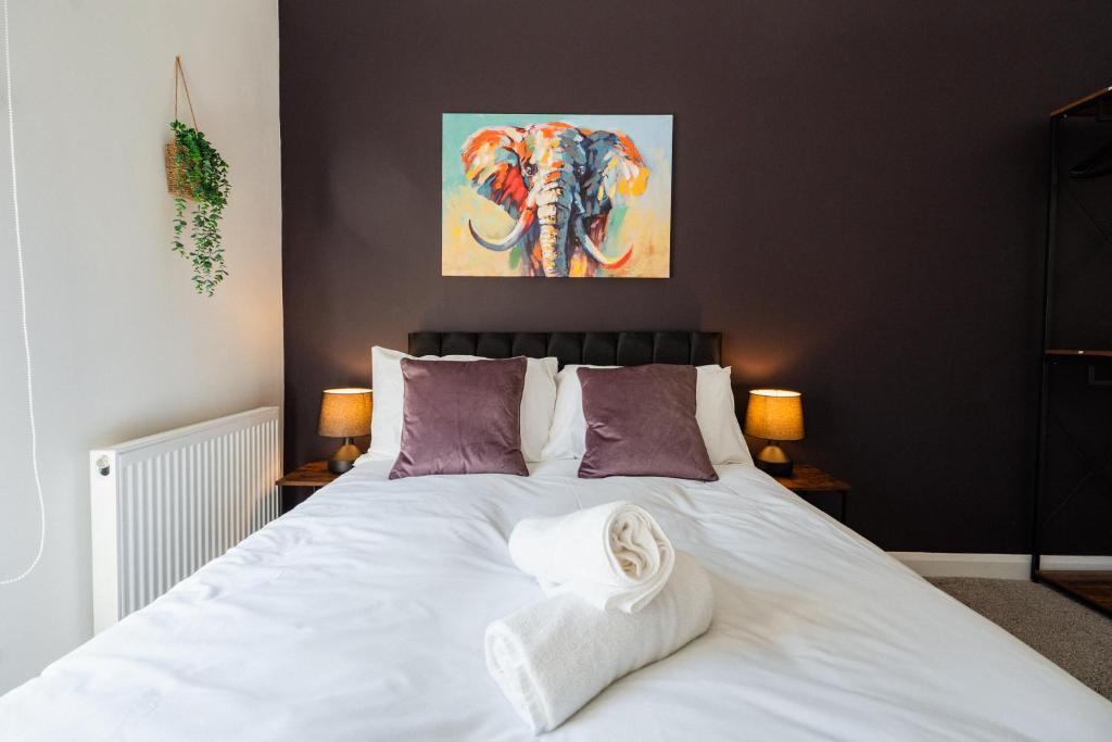 een slaapkamer met een wit bed met een schilderij aan de muur bij The Bishops Nest in Bishop Auckland