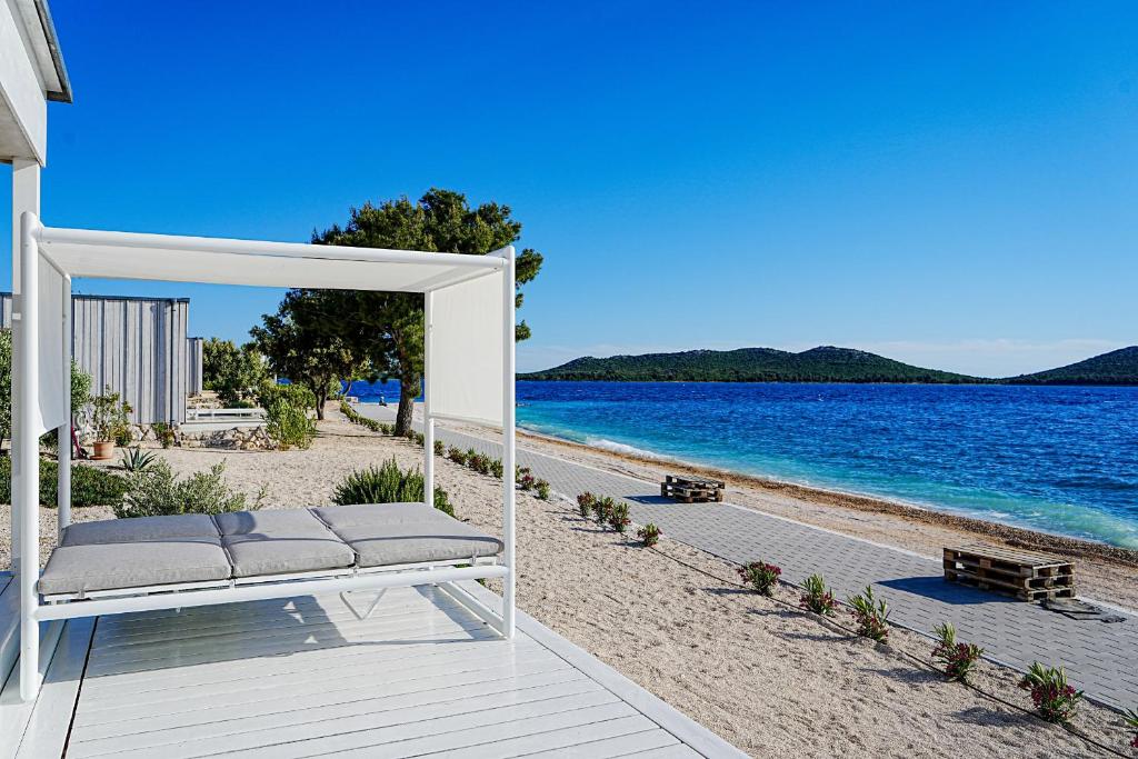 eine weiße Bank am Strand in der Nähe des Wassers in der Unterkunft Buqez Eco Resort - Beach Villa 22 in Drage