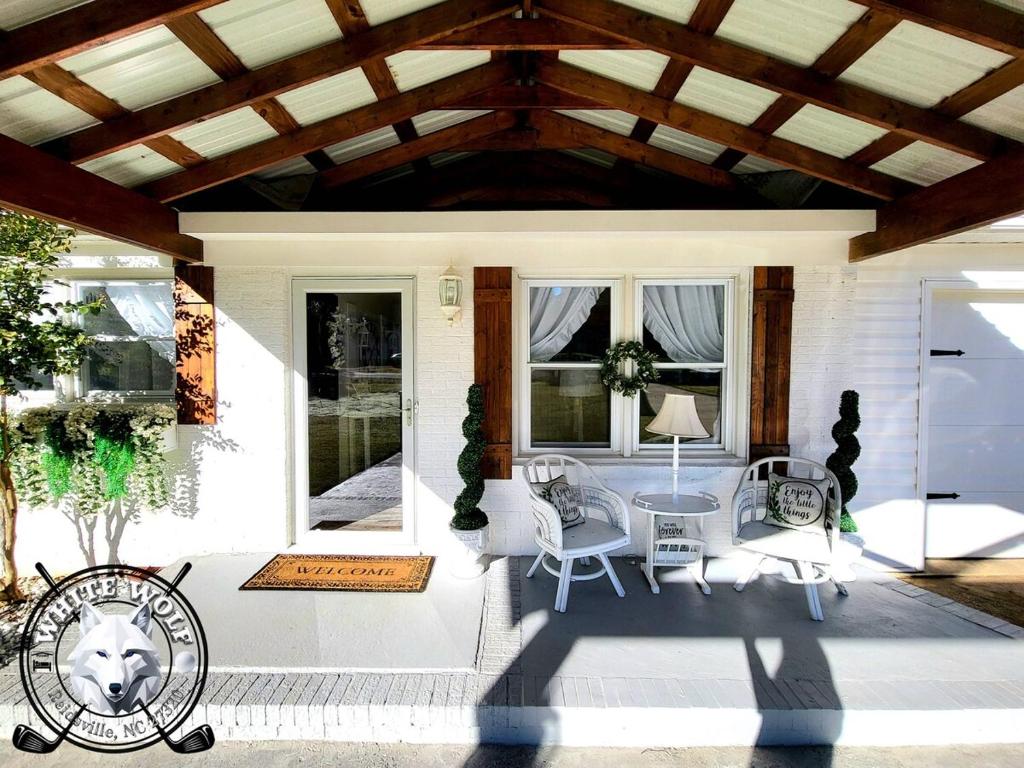 eine Terrasse mit einem Tisch und Stühlen auf einem Haus in der Unterkunft WHITE WOLF Farmhouse Retreat in Reidsville