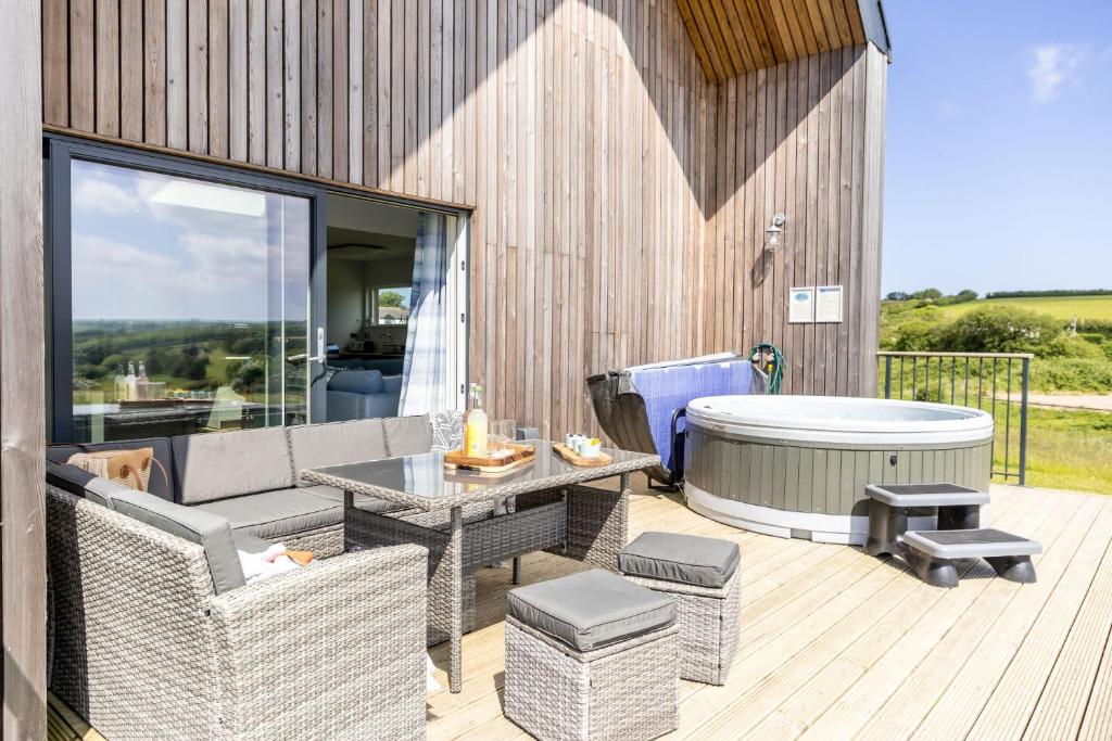 a patio with a table and a tub on a deck at No 2 The Vista, Willingcott, Woolacombe in Woolacombe