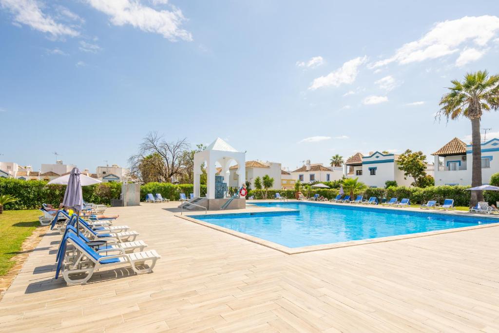 een zwembad in een resort met ligstoelen en een parasol bij Algarve 3-Bedroom Villa w Pool, Beaches & Golf in Tavira