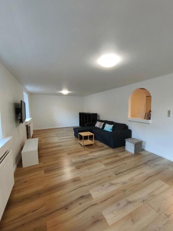 a living room with a black couch and wooden floors at Riverview Cottage in Randbøl