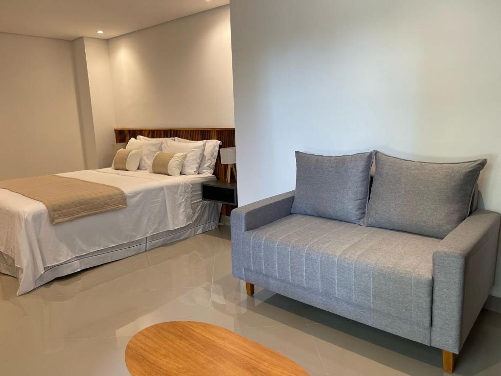 een slaapkamer met een bed en een bank bij Maluhia Ilhabela 1 in Ilhabela