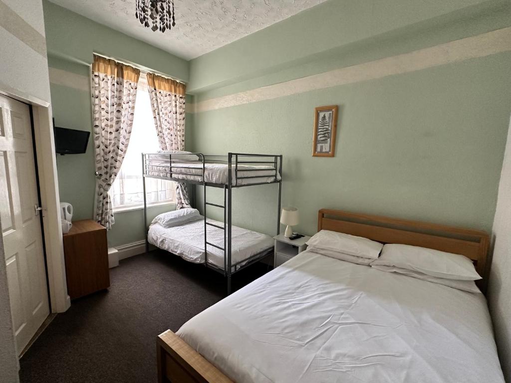 Un dormitorio con dos literas y una ventana. en Alondra Hotel, en Blackpool