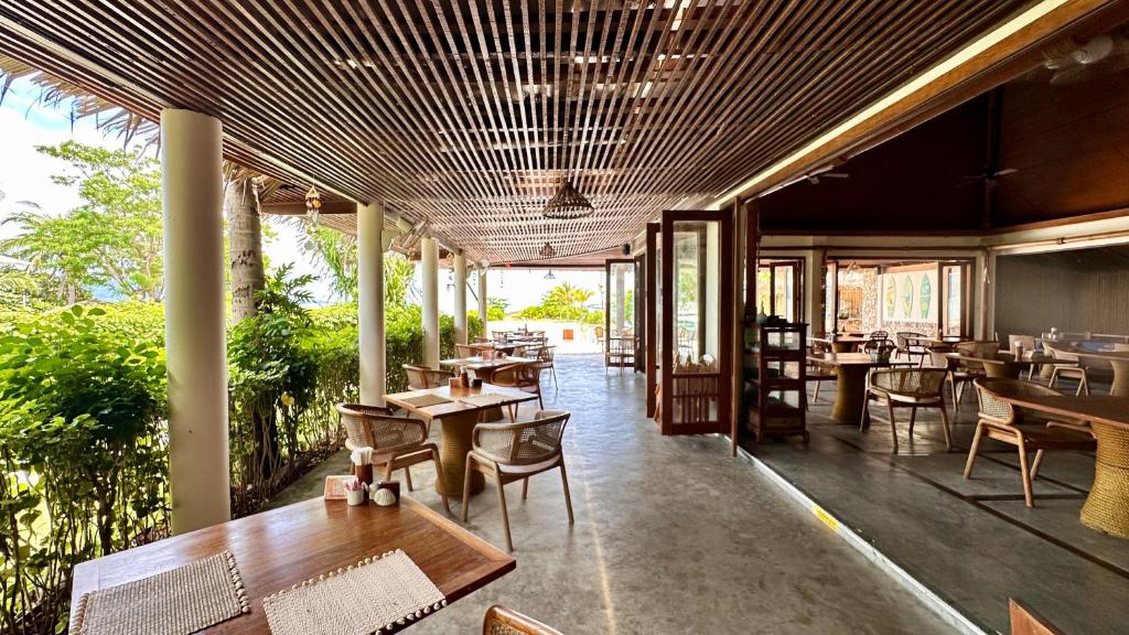 a restaurant with wooden tables and chairs and windows at Deva Beach Resort Samui in Choeng Mon Beach