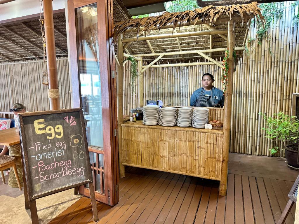 a man standing behind a counter with plates at Deva Beach Resort Samui in Choeng Mon Beach