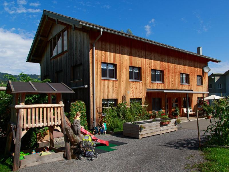 ein Holzhaus mit einem Spielplatz davor in der Unterkunft Apart Greber in Andelsbuch