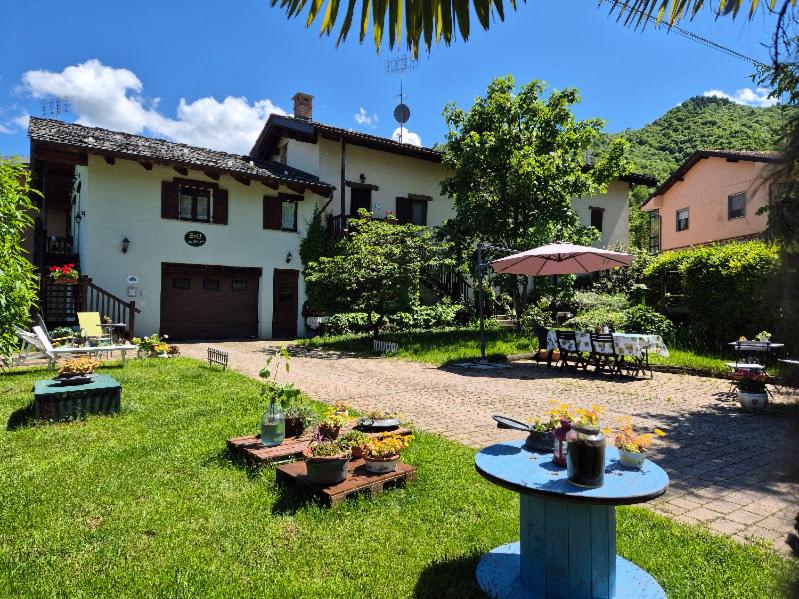 ein Hof mit Tischen, einem Sonnenschirm und einem Haus in der Unterkunft B&B Alla Borgata in Boves