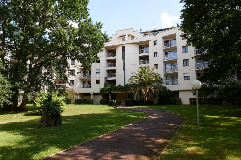 - un grand immeuble blanc avec une pelouse dans l'établissement Residence Les Chenes, à Saint-Paul-lès-Dax