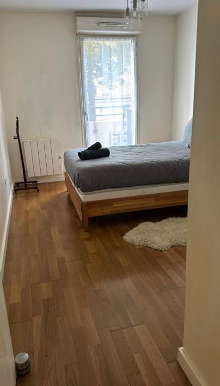 - une chambre avec un lit, du parquet et une fenêtre dans l'établissement Appartement Cosy, à Fresnes