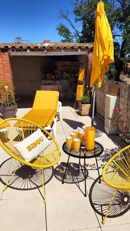 une terrasse avec une table jaune, des chaises et un parasol dans l'établissement Escale vélo La petite Reine, à Cavaillon
