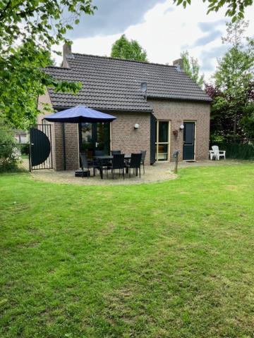 a house with a table and chairs in a yard at Forest Vacation Home -fenced garden- in Ewijk