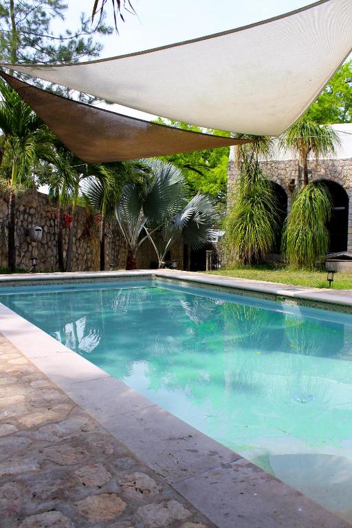 a swimming pool with a hammock over it at Hotel Boutique Canto De Piedra in Tamasopo