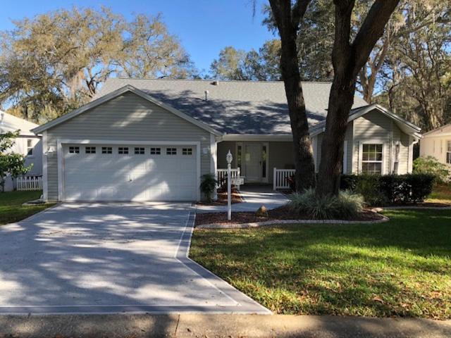 a white house with a garage and a tree at 119 Z2b VILLAGE LA ZAMORA by REMAX Premier in The Villages