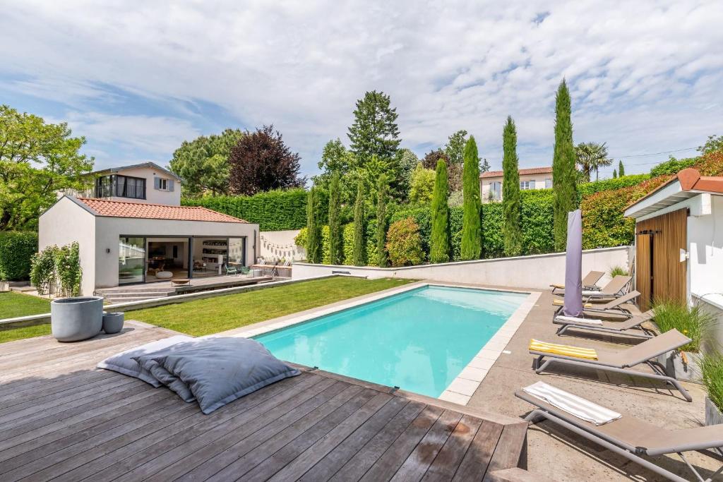- une piscine dans un jardin avec des chaises et une maison dans l'établissement La Radieuse, à Saint-Didier-au-Mont-dʼOr