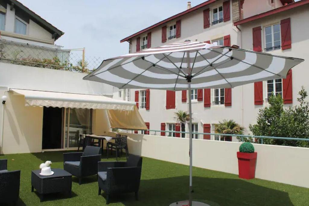 une terrasse avec un parasol en face d'un bâtiment dans l'établissement Appartement tout à pied à Biarritz centre, à Biarritz