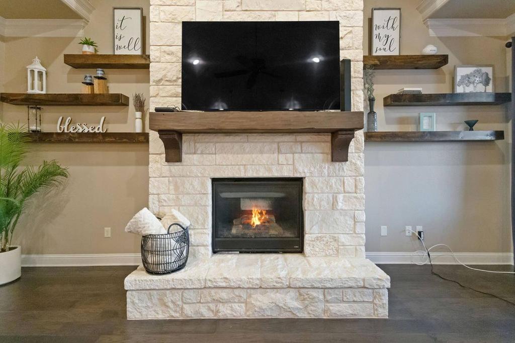 un salon avec une cheminée en pierre avec une télévision à écran plat dans l'établissement Luxe Retreat: Pool, Spa,Jacuzzi, EV Charger & more, à DeCordova