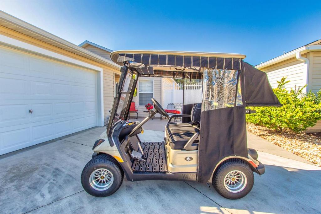 un carro de golf estacionado frente a un garaje en 2332 Z3B VILLAGE OF HADLEY by REMAX Premier, en The Villages
