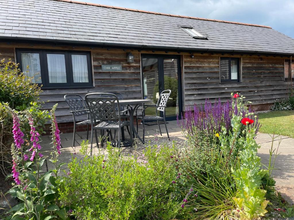a house with a table and chairs and flowers at Oak Apple in Plaitford