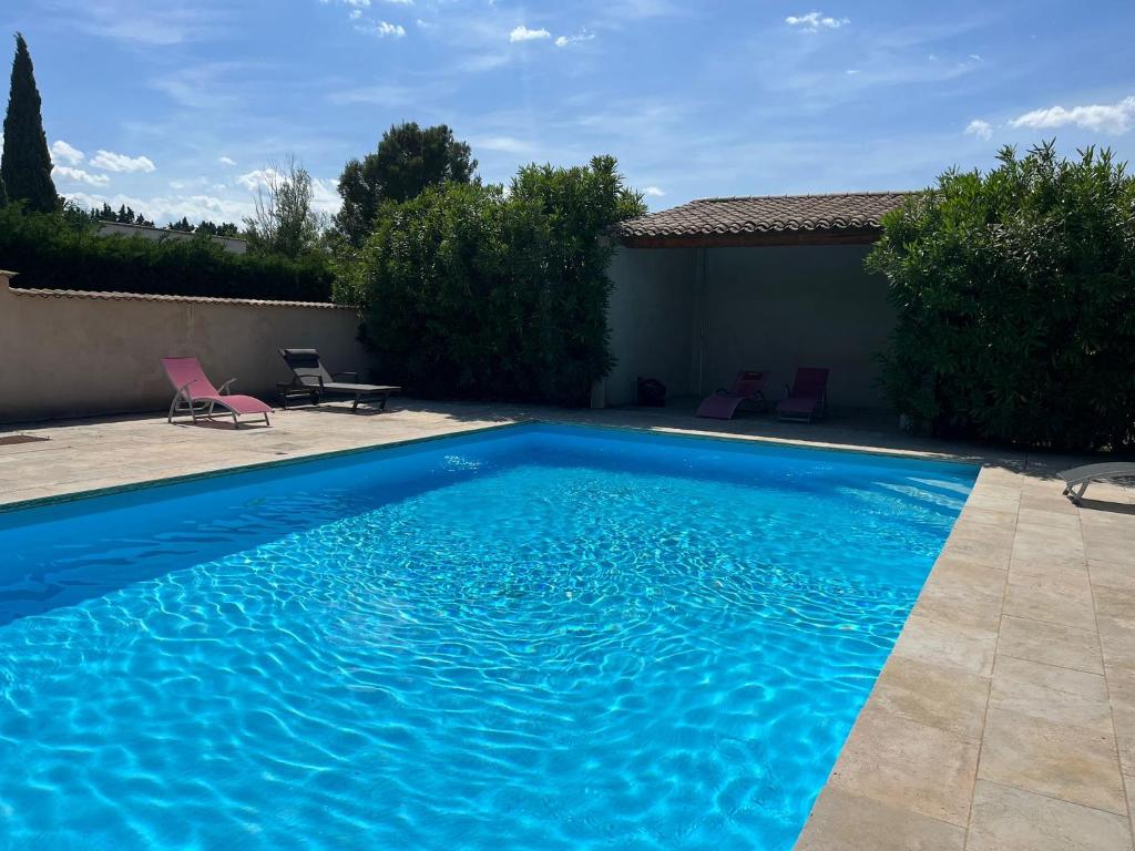 - une piscine bleue avec 2 chaises dans la cour dans l'établissement Premier gîte du mas, à Lagnes