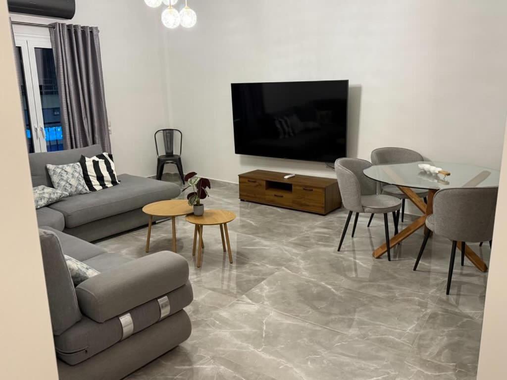 a living room with a couch and a tv and a table at Hotspot Acharnes in Akharnaí
