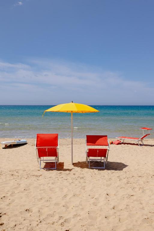 two chairs and an umbrella on the beach at Residence Le 4 Stagioni in Menfi