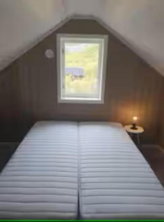 a bed in a room with a small window at Explorers Cabin Lofoten in Offersøya