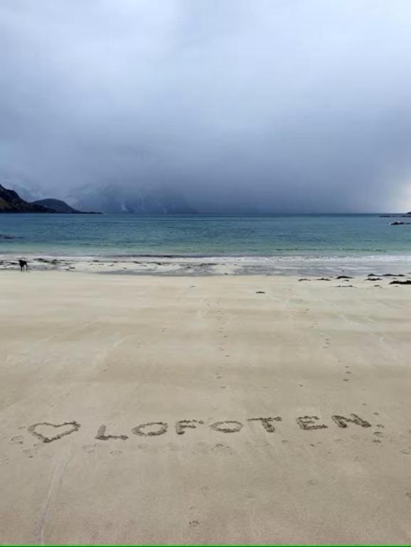 a sign written in the sand on a beach at Explorers Cabin Lofoten in Offersøya