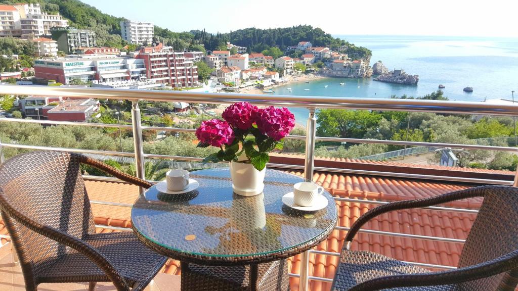 a table with a vase of flowers on a balcony at Apartments Rino Lux in Sveti Stefan