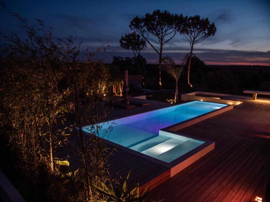 a swimming pool in a backyard at night at Casa Thala - Conceptual 3-Suite Villa & Hot Pool in Alcácer do Sal