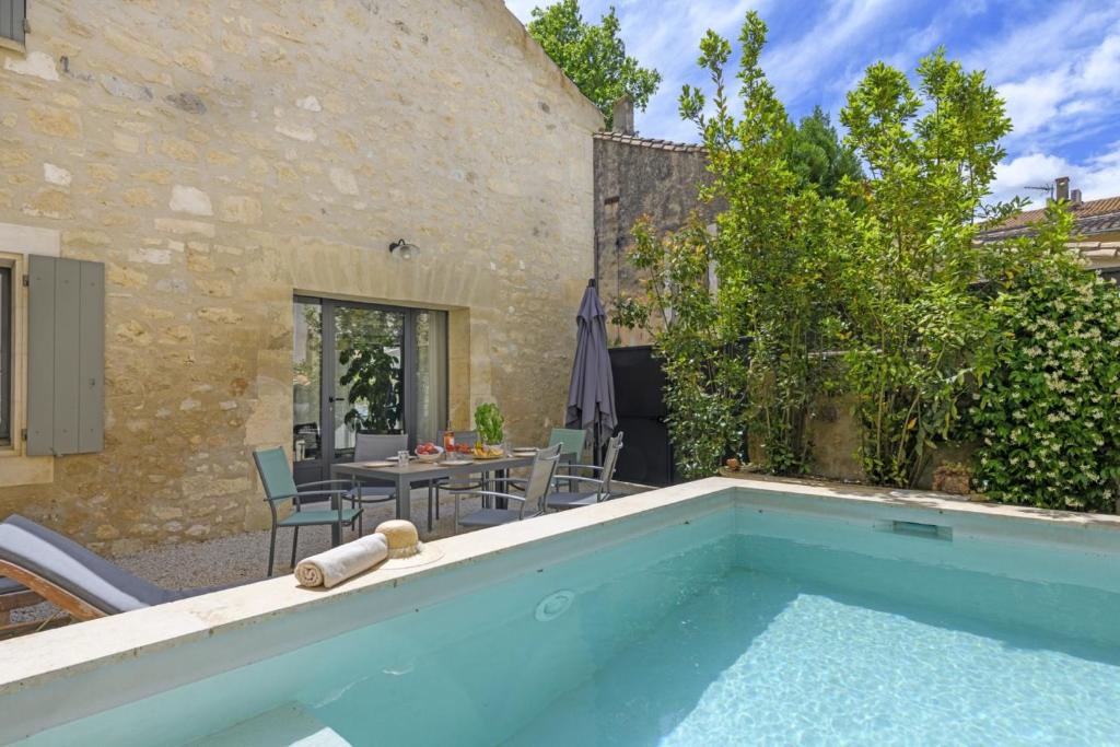une piscine extérieure avec une table et des chaises et un bâtiment dans l'établissement La Petite Maussanaise, à Maussane-les-Alpilles