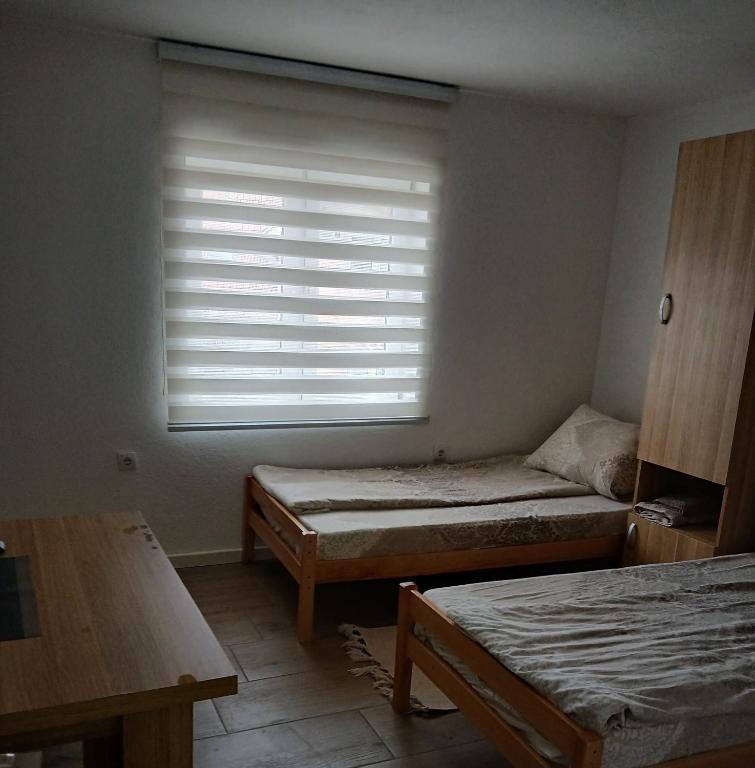 a room with two beds and a window with blinds at Soba Ðorović 3 in Postenje