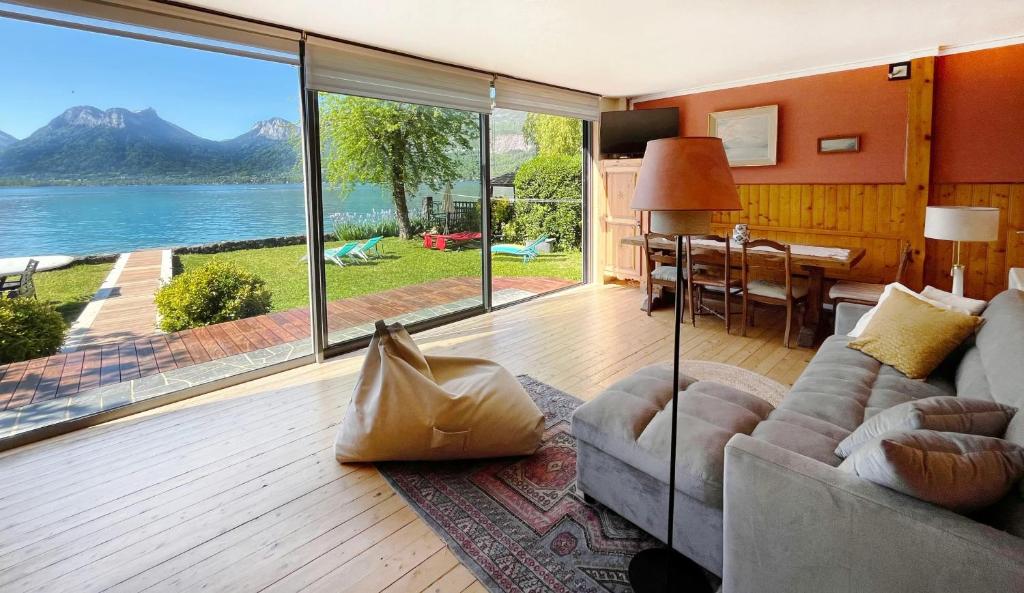 a living room with a couch and a large window at Chalet les pieds dans l'eau avec accès direct au Lac d'Annecy in Angon
