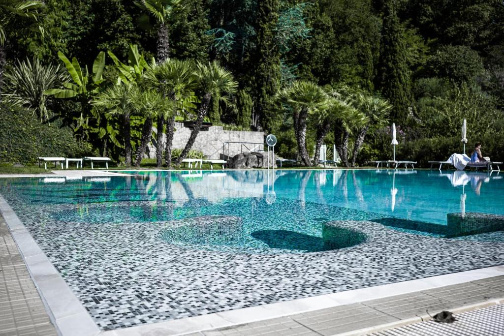Una gran piscina con agua azul y palmeras. en Hotel Terme Millepini, en Montegrotto Terme