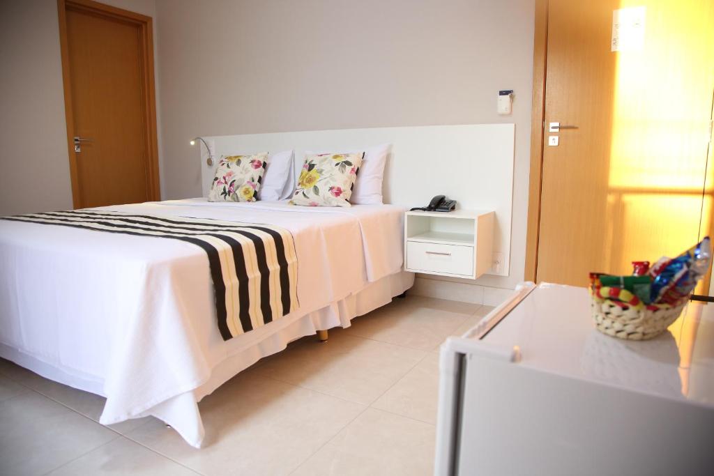 een slaapkamer met een wit bed en een zwart-witte deken bij Ventura Hotel in Barreiras