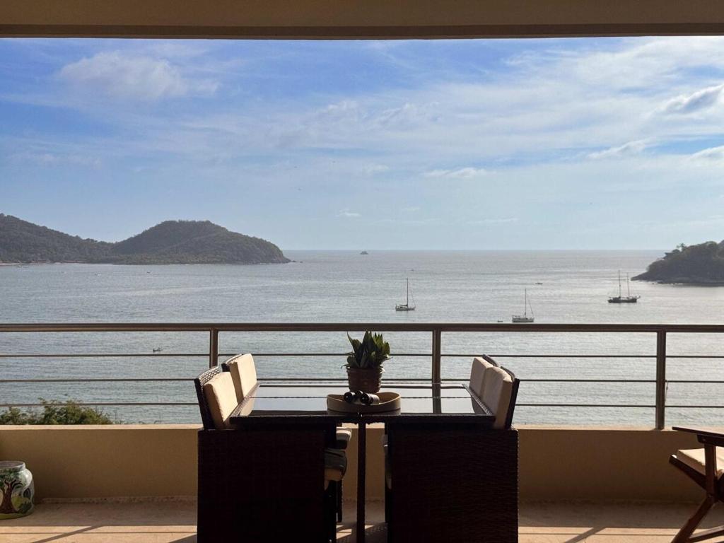 ein Tisch mit Stühlen und Blick auf das Meer in der Unterkunft Luxury Penthouse at Aura del Mar in Zihuatanejo