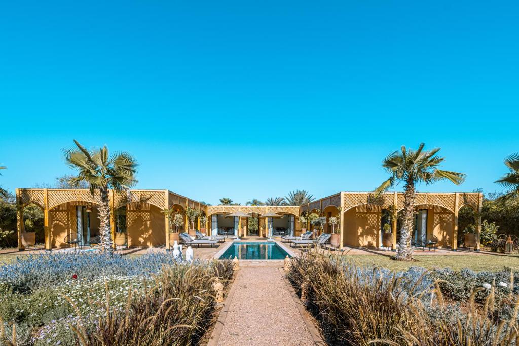 an exterior view of a house with a swimming pool and palm trees at Villa Naël Marrakech in Marrakech