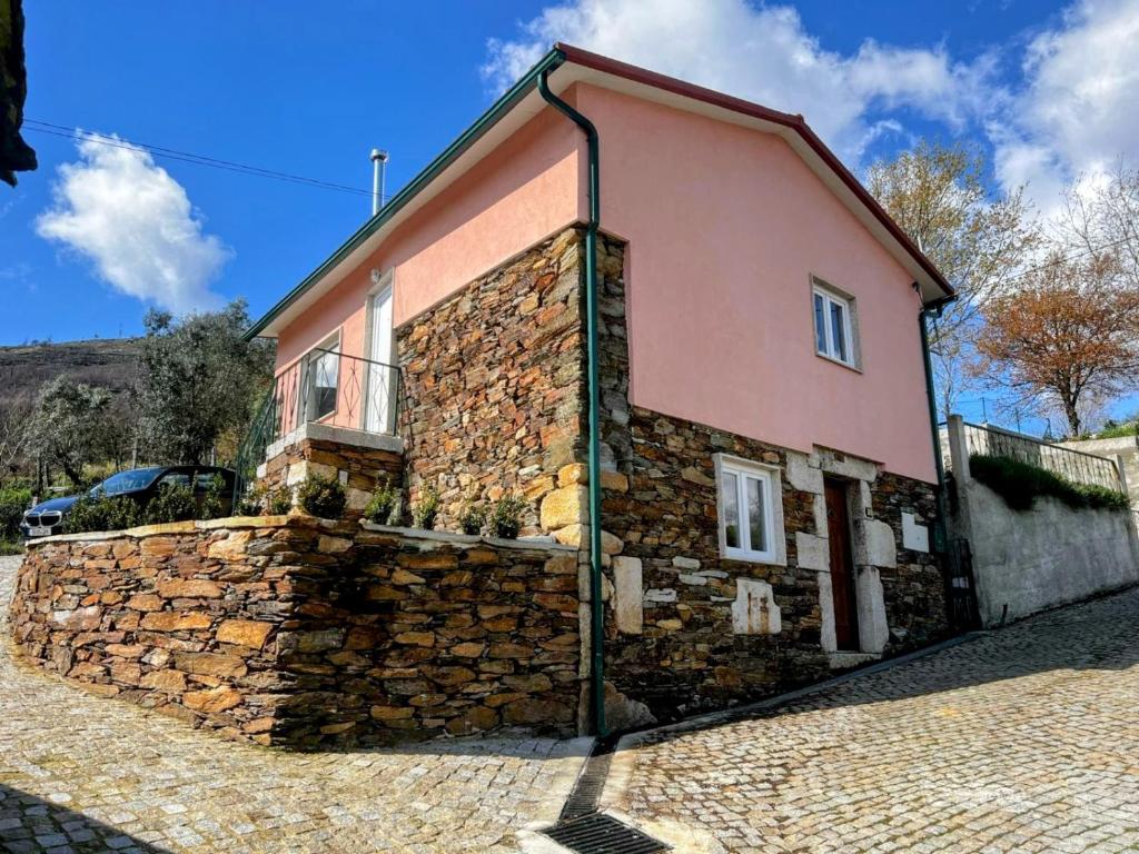 ein Gebäude mit einer Steinmauer neben einem Haus in der Unterkunft Casas Cor de Rosa in São Martinho das Moitas