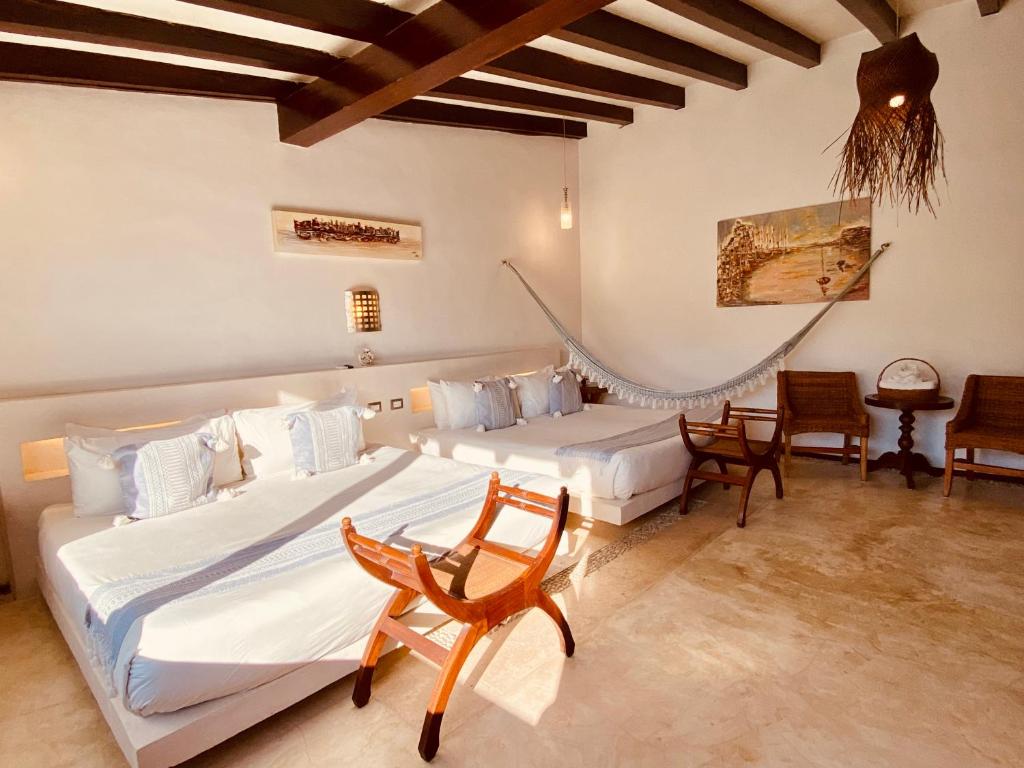 a bedroom with two beds and a table and chairs at Hotel Para Ti - Adults Only in Holbox Island