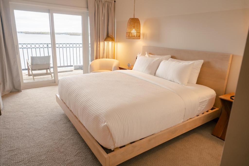 a bedroom with a large white bed and a balcony at The Shoreline Hotel in Spring Park