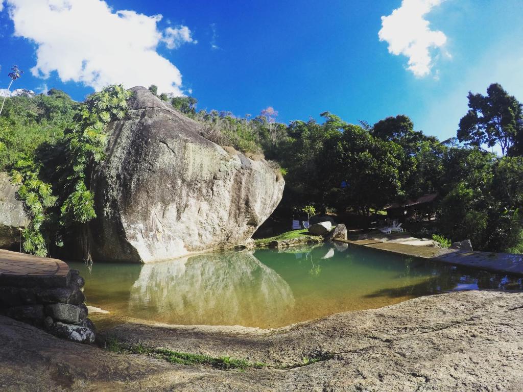 una piscina d'acqua di fronte a una grande roccia di Pousada Paraiso a Itaipava
