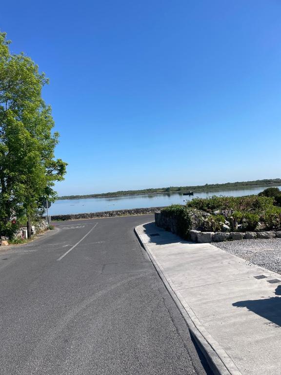 an empty road next to the ocean on a sunny day at Glebe cottage in Kinvara