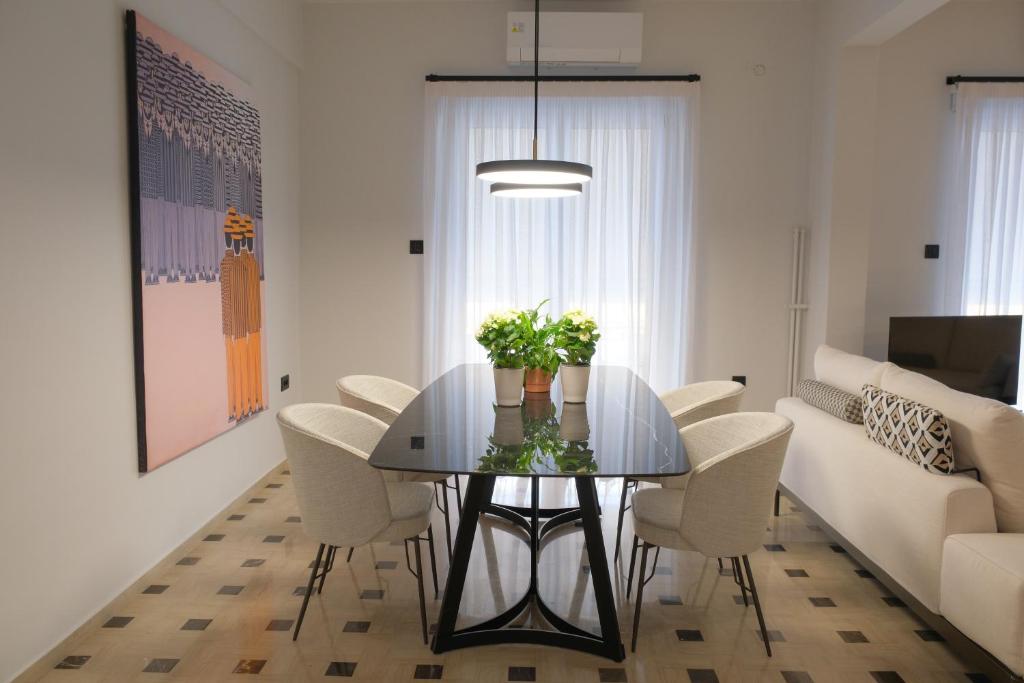a dining room with a glass table and white chairs at AD ASTRA Comfort Living in Preveza