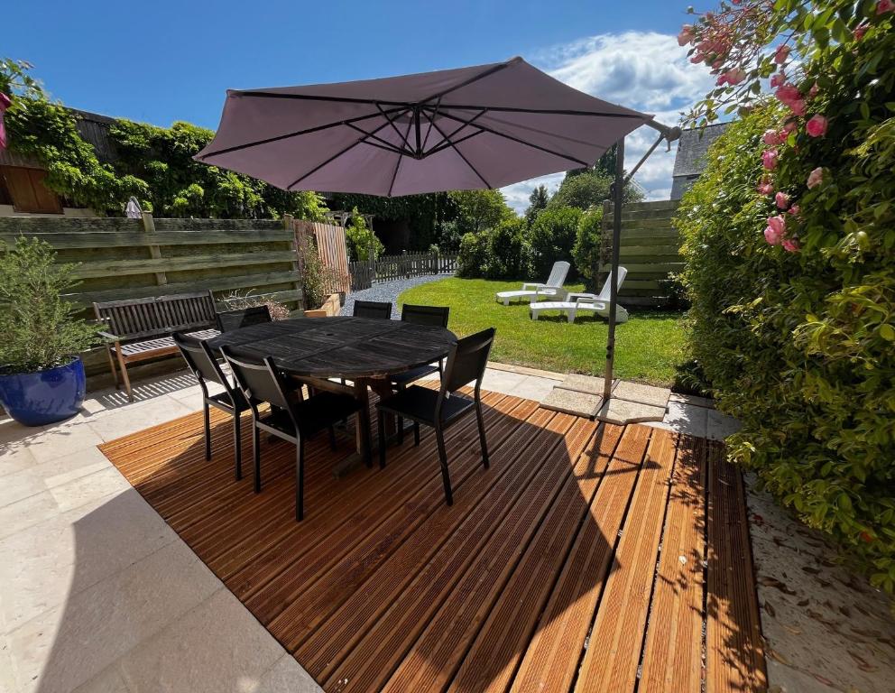 une table noire avec des chaises et un parasol sur une terrasse dans l'établissement Le Moulin de la Fosse Soucy 