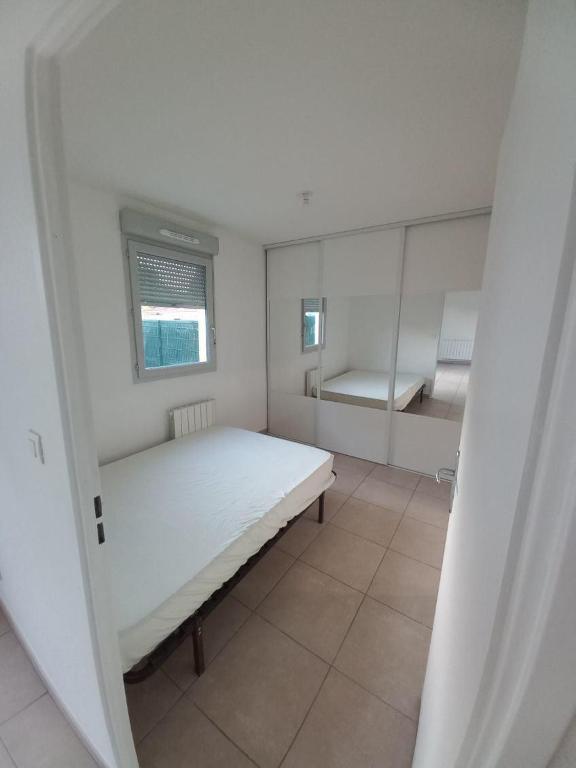 une chambre blanche avec un lit et une fenêtre dans l'établissement T2 Villefranche, à Villefranche-sur-Saône