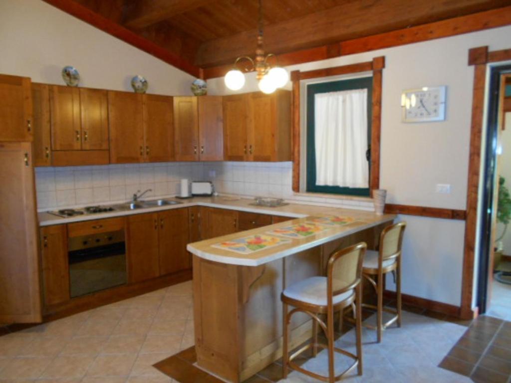 a kitchen with wooden cabinets and a counter with chairs at GiaMia Villas -Rural Central Italy Paradise in Sulmona